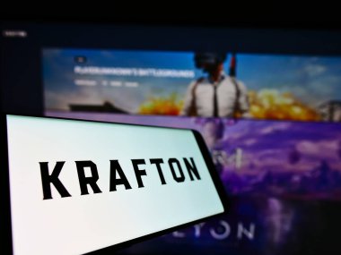 STUTTGART, GERMANY - Jun 14, 2021: Cellphone with logo of South Korean video games company Krafton Inc. on screen in front of website. Focus on center-left of phone display. clipart