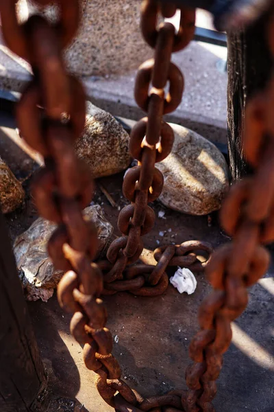 太陽の下で古い木片の上に錆びた鉄の鎖を考える垂直ショット — ストック写真
