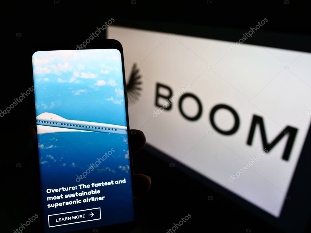 STUTTGAR, GERMANY - Jun 07, 2021: Person holding cellphone with webpage of US aviation company Boom Technology Inc. (Supersonic) on screen with logo. Focus on center of phone display.