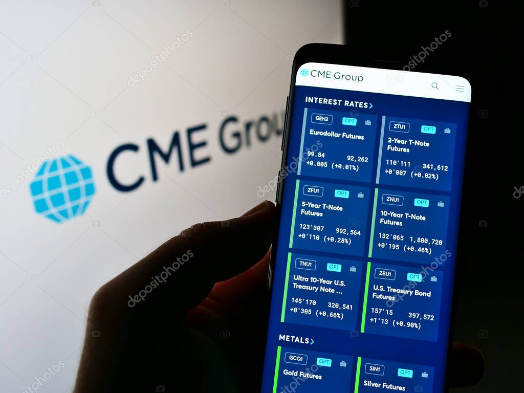 STUTTGART, GERMANY - Jun 07, 2021: Person holding cellphone with webpage of US financial services company CME Group Inc. on screen in front of logo. Focus on center of phone display.