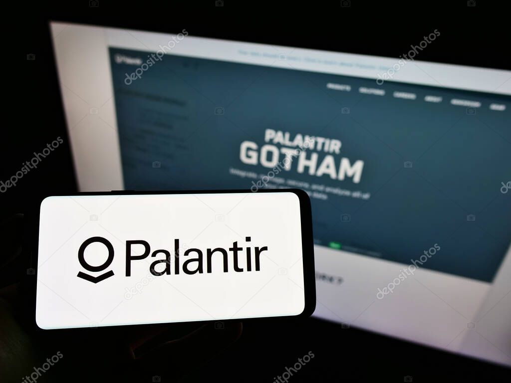 STUTTGART, GERMANY - Jun 07, 2021: Person holding mobile phone with logo of American software company Palantir Technologies Inc. on screen in front of web page. Focus on phone display.