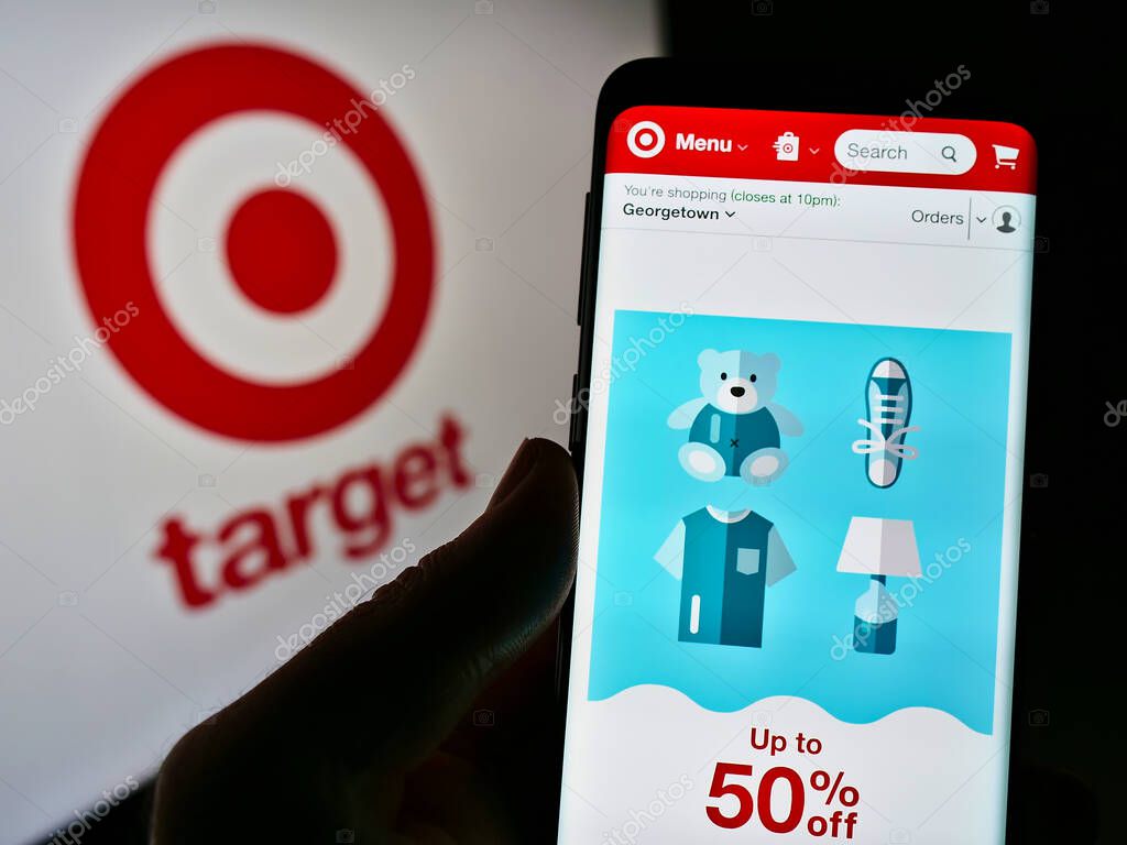 STUTTGART, GERMANY - Jun 03, 2021: Person holding cellphone with web page of American retail company Target Corporation on screen in front of logo. Focus on center of phone display.
