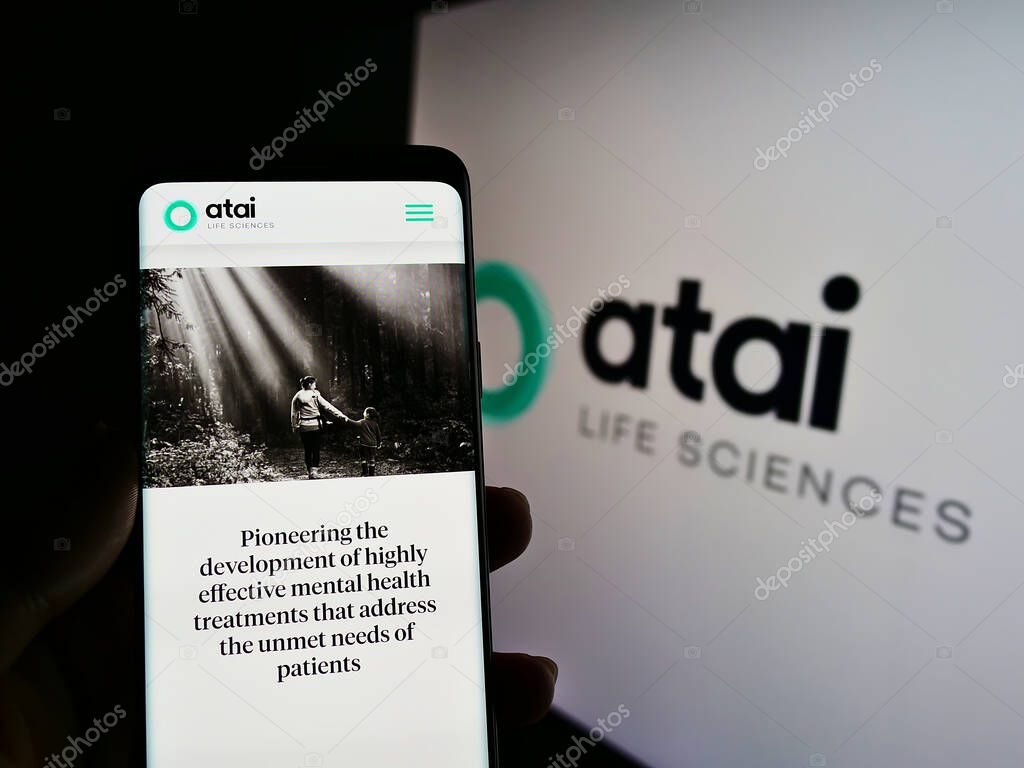 STUTTGART, GERMANY - Jun 14, 2021: Person holding smartphone with website of German biotech company ATAI Life Sciences AG on screen in front of logo. Focus on center of phone display.