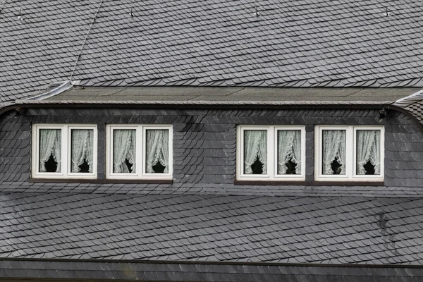用旧建筑的窗户拍摄的瓷砖屋顶的灰度照片 — 图库照片