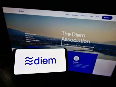 STUTTGART, GERMANY - May 31, 2021: Person holding smartphone with logo of cryptocurrency organization Diem Association on screen in front of website. Focus on phone display. clipart