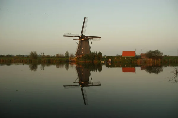 Een Reflecterend Meer Met Een Windmolen Onder Een Heldere Hemel — Stockfoto