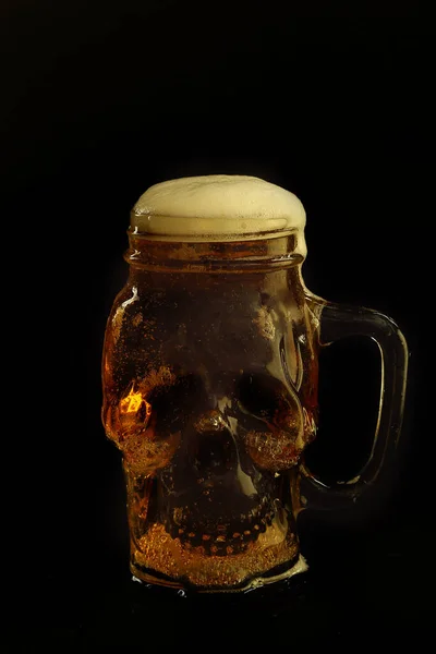 在黑色背景下隔离的头骨玻璃杯中的啤酒 — 图库照片