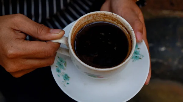 Zbliżenie Ludzkich Rąk Trzymających Filiżankę Czarnej Kawy Spodkiem — Zdjęcie stockowe