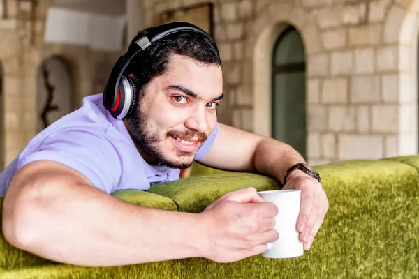 Joven Atractivo Sonriente Hombre Oriente Medio Apoyado Espalda Sofá Sosteniendo —  Fotos de Stock