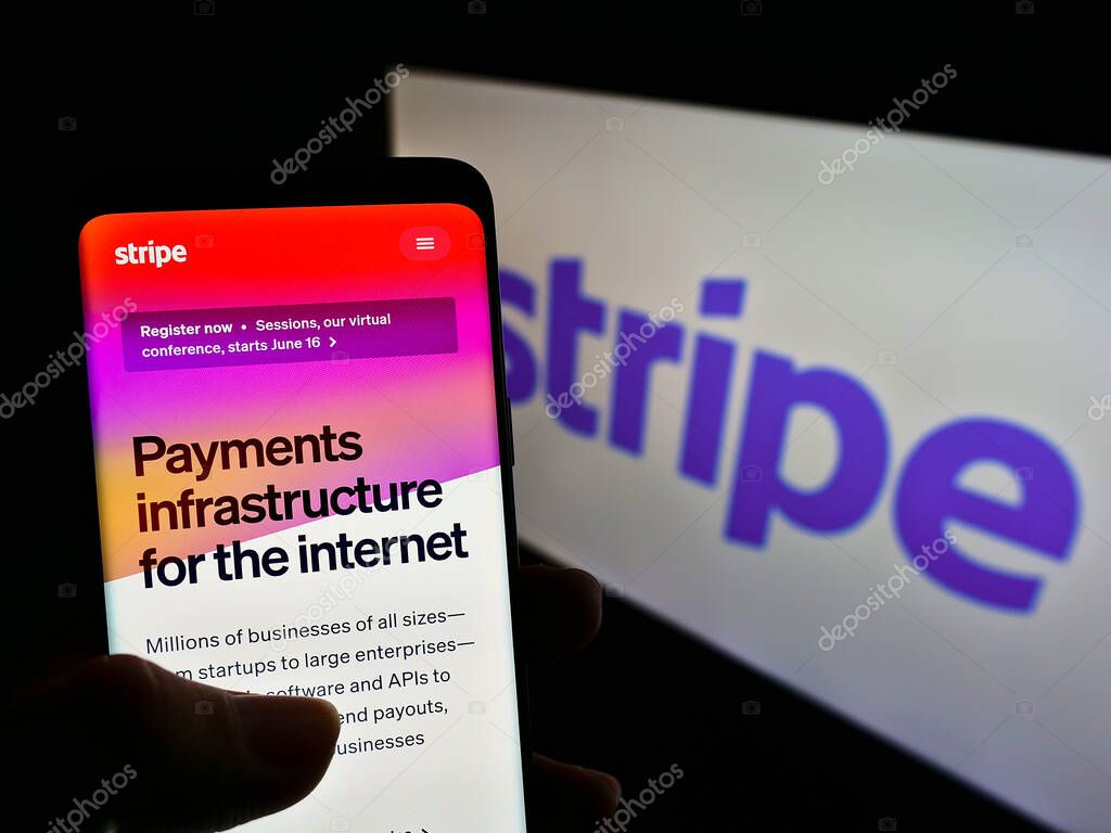 STUTTGART, GERMANY - May 26, 2021: Person holding mobile phone with webpage of Irish-US financial services company Stripe Inc. on screen with logo. Focus on center of phone display.