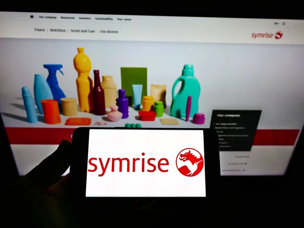 发自德国Stuttga 2021年5月18日 持有带有德国风味和香水公司Symrise Ag标志的手机的人出现在网页前的屏幕上 专注于手机显示 — 图库照片