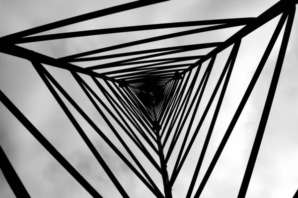 曇り空を背景にした金属製のタワーパターンのモノクロのボトムショット — ストック写真