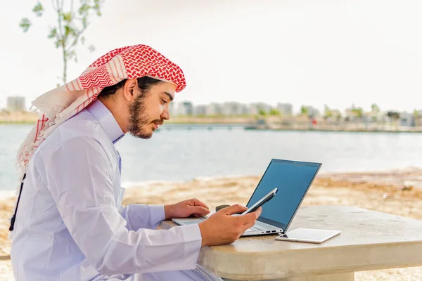 Arabisk Man Som Arbetar Telefon Och Bärbar Dator Vid Havsområdet — Stockfoto