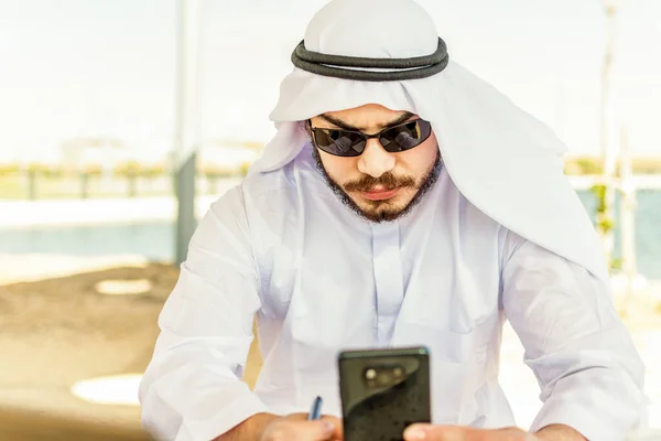 Arabisk Man Traditionell Trasa Sitter Parken Kollar Sin Mobiltelefon — Stockfoto