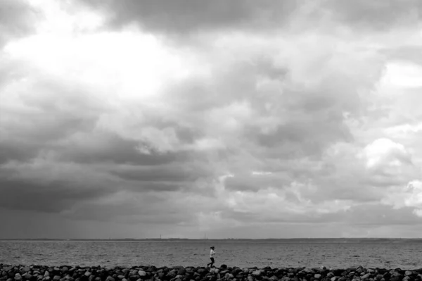 Bulutlu Bir Gökyüzünün Altında Sahilde Tek Başına Koşan Bir Kadının — Stok fotoğraf