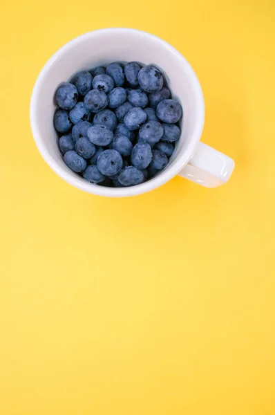 Plan Vertical Bleuets Dans Une Tasse Sur Fond Jaune — Photo