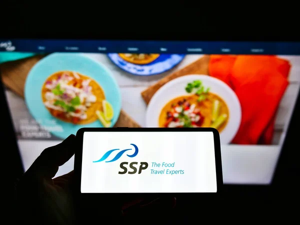 stock image STUTTGART, GERMANY - Mar 03, 2021: Person holding cellphone with business logo of British food service company SSP Group plc on screen in front of website. Focus on phone display.