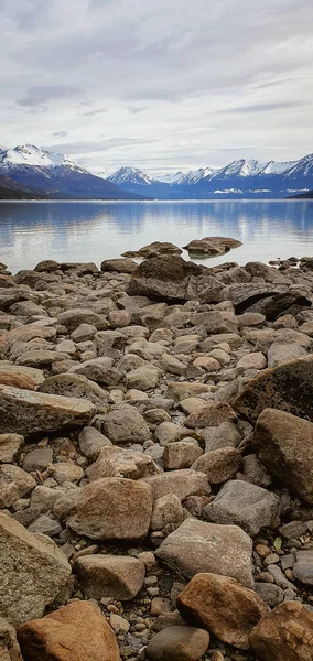 Vertical Shot Breakwater Stones Seaside Front Mountains Covered Snow — Stok Foto