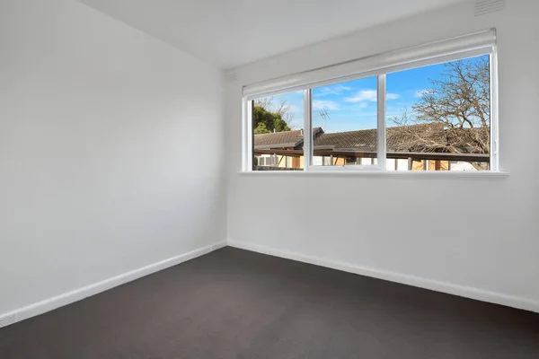 stock image A corner of a new empty room with white walls, windows, and black floor