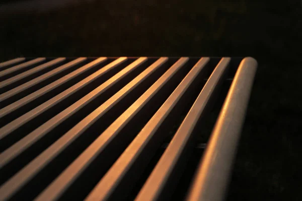 Gün Batımının Turuncu Işığını Yansıtan Metal Bir Bankın Yakın Çekimi — Stok fotoğraf