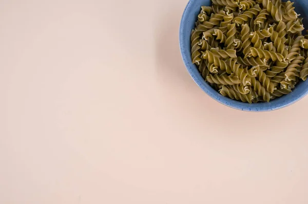 Tiro Vertical Massa Fusilli Italiana Uma Tigela Azul Fundo Bege — Fotografia de Stock