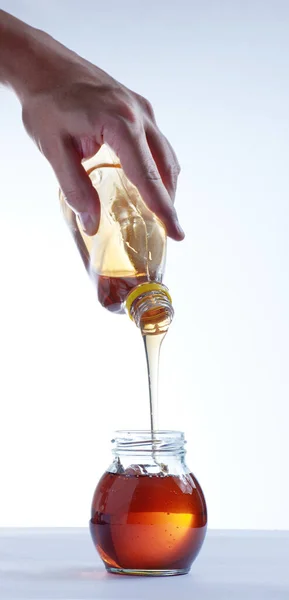 Disparo Vertical Una Mano Vertiendo Miel Botella Frasco Sobre Fondo — Foto de Stock