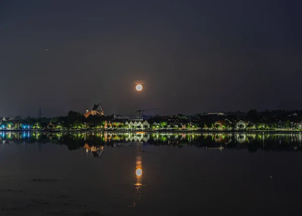 满月映照在湖面上 湖岸上有一座城市 — 图库照片