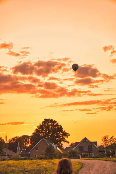 Colpo Verticale Una Mongolfiera Cielo Luminoso Arancio Tramonto Una Città — Foto Stock