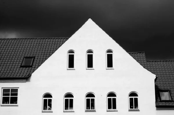 Monochrome Shot White Facade Building Triangle Roof Dark Cloudy Sky — Stock Photo, Image