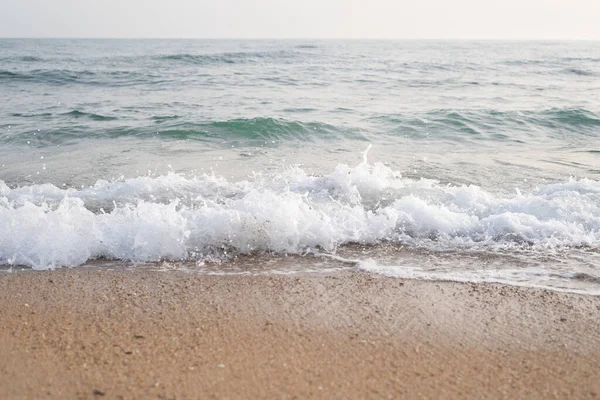 Een Schuimige Golf Van Zee Een Zandstrand — Stockfoto