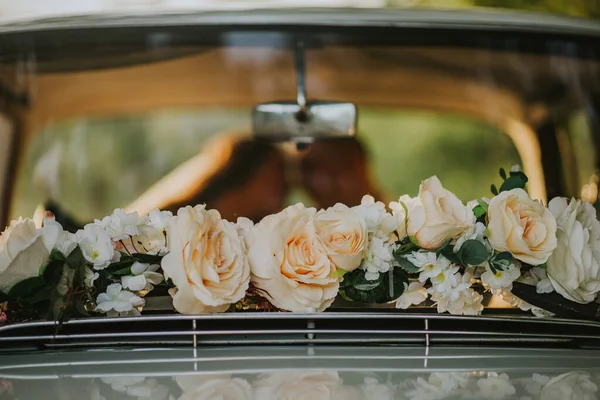 The fresh white roses on a wedding car\'s rear glass window