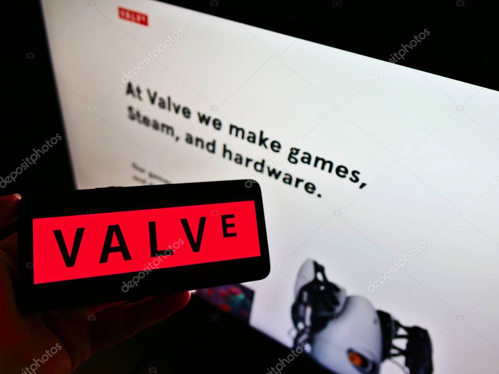 STUTTGART, GERMANY - Feb 19, 2021: Person holding smartphone with logo of American video game company Valve Corporation on screen in front of business web page. Focus on phone display.
