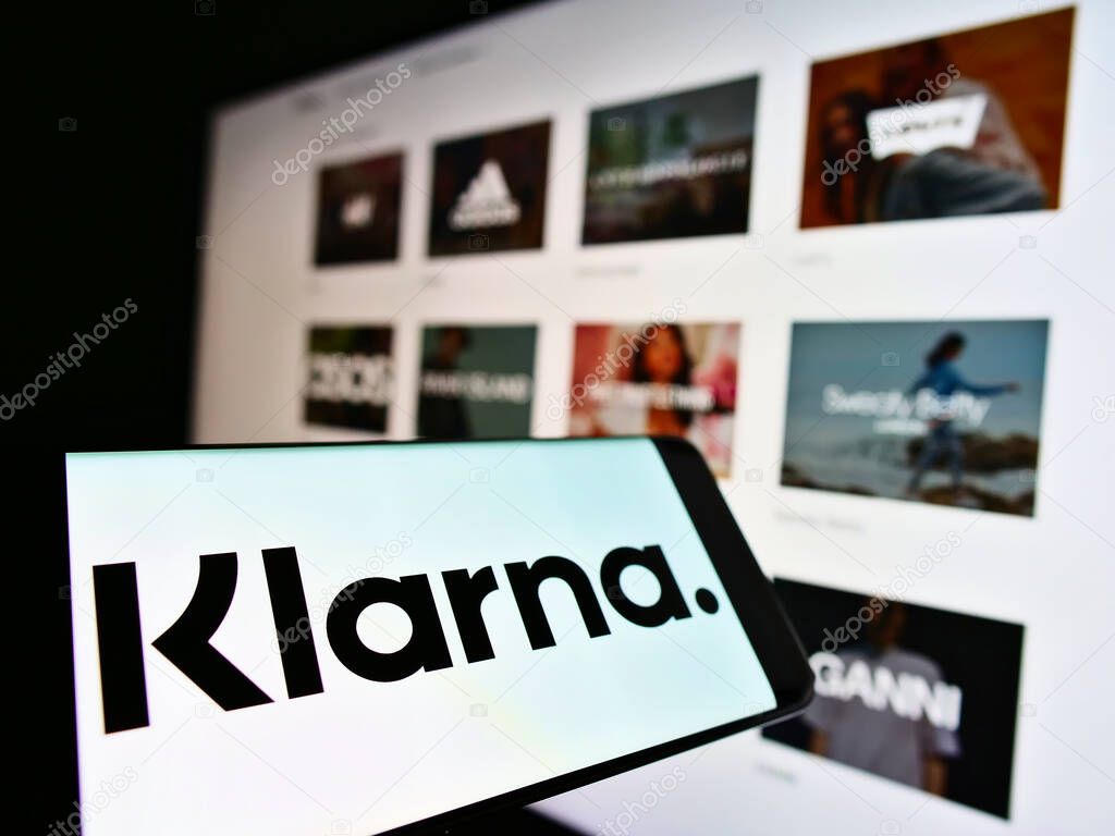 STUTTGART, GERMANY - Mar 03, 2021: Mobile phone with logo of Swedish payment company Klarna Bank AB on screen in front of web page. Focus on center of cellphone display.