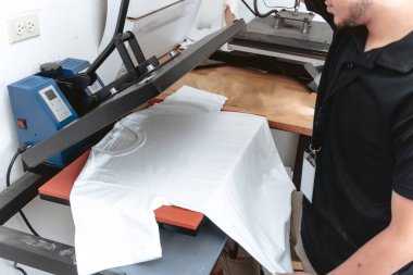A young Caucasian man using an iron sublimation to design a white t-shirt clipart