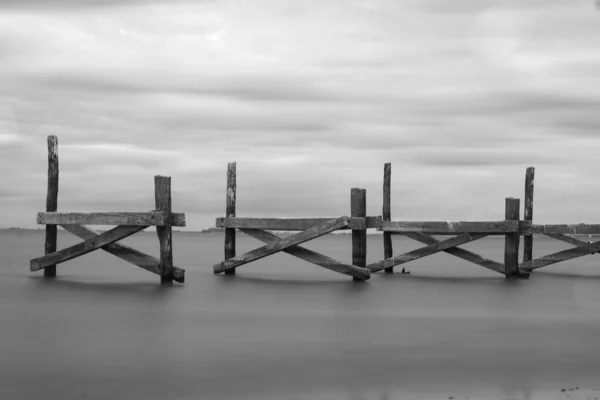 Grayscale Záběr Starého Dřevěného Mostu Moři Dlouhou Expozicí — Stock fotografie