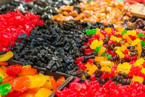 Assortment of gummies, liquorice and gummy bears piled up for flavors in an outdoor market. Close up.
