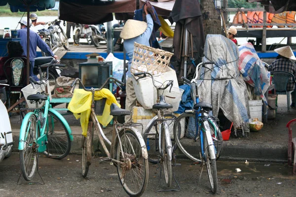 オープンエアのフリーマーケットでの古い駐車自転車は 典型的なアジアの米の帽子を身に着けている売り手と — ストック写真