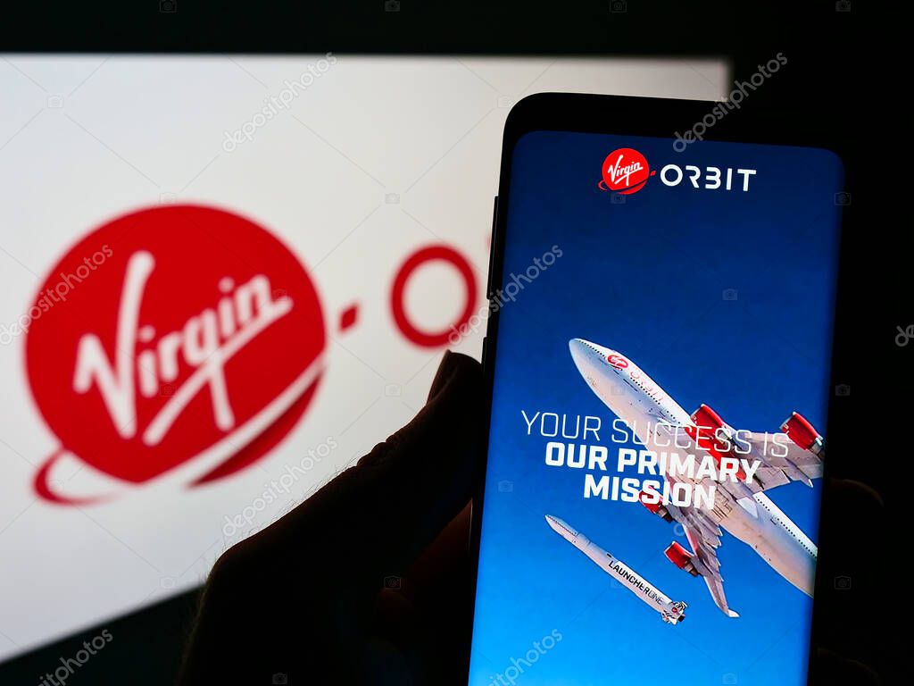 STUTTGART, GERMANY - Sep 05, 2021: Person holding smartphone with website of company Virgin Orbit LLC on screen in front of logo. Focus on center of phone display.