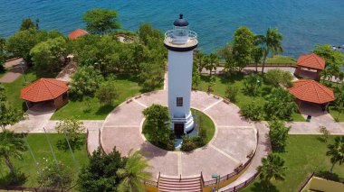 A drone view of the Punta Higuero Light surrounded by palm trees and the sea in Puerto Rico clipart