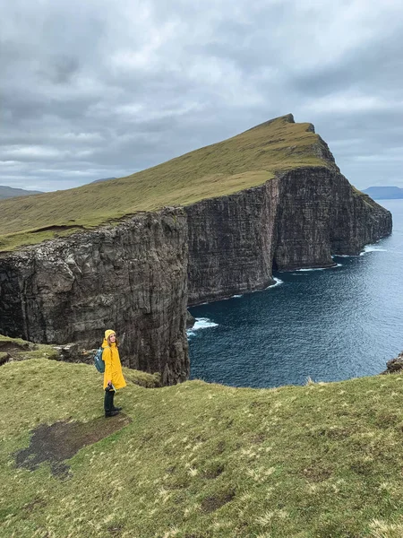 Female Tourist Yellow Raincoat Standing Cliff Dramatic Scandinavian Background Towering — Stock Photo, Image