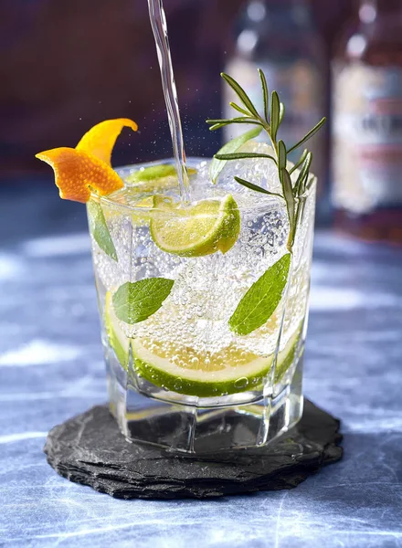 Colpo Verticale Gin Tonico Versato Bicchiere Con Fette Rosmarino Lime — Foto Stock