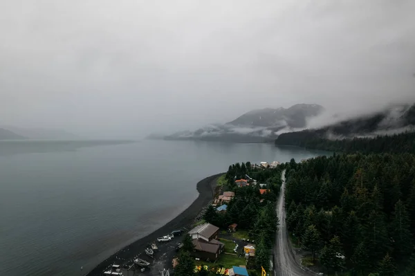 アラスカの湖と山に囲まれた田舎の町の上に霧の朝の空中ショット — ストック写真