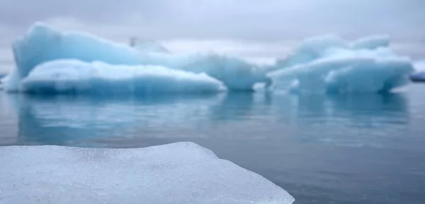 アイスランドのジョクルサロン氷河ラグーンでの冬の朝 背景に巨大な氷山がぼやけています — ストック写真
