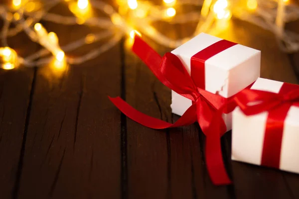 圣诞彩灯和礼品盒 红色缎带在破旧的木制背景上 — 图库照片