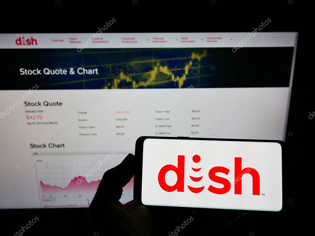 STUTTGART, GERMANY - Sep 12, 2021: Person holding mobile phone with logo of company DISH Network Corporation on screen in front of web page. Focus on phone display.