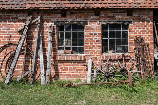 前に道具や錆びた機器を備えたレンガ造りの家 — ストック写真