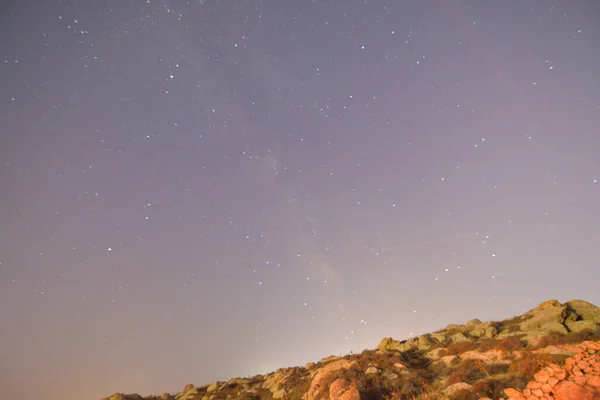 Cudowne Jasnofioletowe Wieczorne Niebo Wypełnione Świecącymi Gwiazdami Nad Skalistym Wzgórzem — Zdjęcie stockowe
