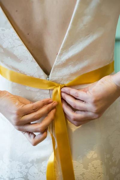 花嫁の垂直閉鎖彼女のドレスに黄色のリボンを結ぶ — ストック写真