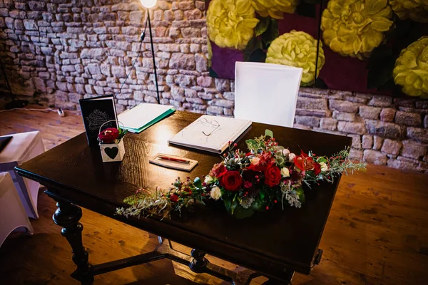 A table at a venue setup for an intimate civil wedding ceremony with a stonewall background