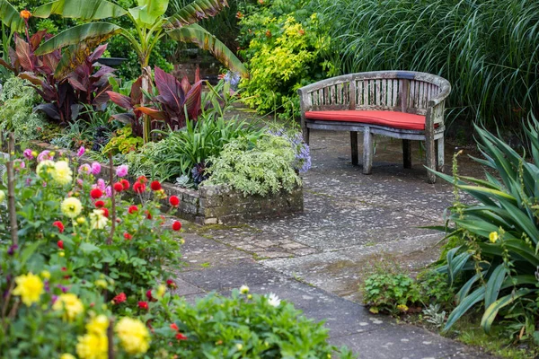 花园里的一张旧木制长椅的特写镜头 上面有美丽的植物和花朵 — 图库照片